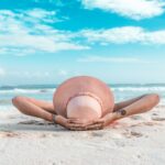 woman in brown sun hat lying on sand during daytime