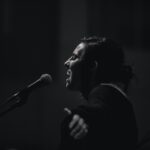grayscale photo of woman standing beside microphone