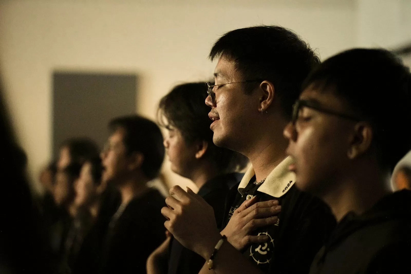 People with eyes closed, hands on chest, singing